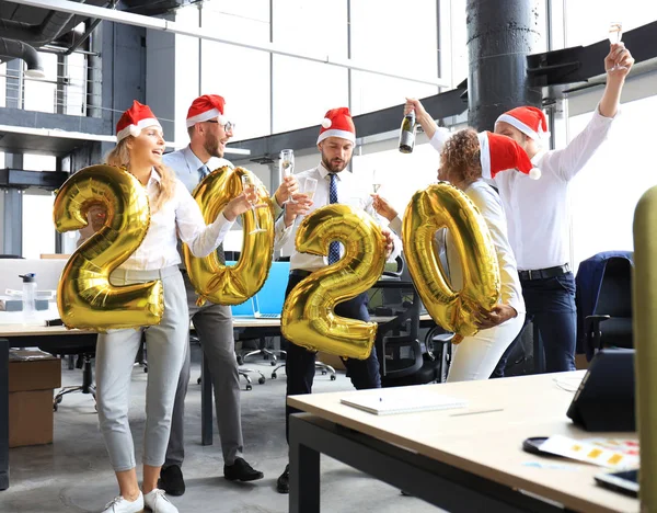 Oamenii de afaceri sărbătoresc vacanța în birourile moderne care beau șampanie și se distrează în coworking. Crăciun fericit și Anul Nou fericit 2020 . — Fotografie, imagine de stoc