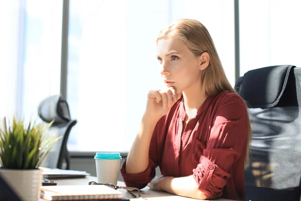 Koncentrovaná moderní žena drží ruku na bradě a přemýšlí o podnikání při práci v kanceláři — Stock fotografie