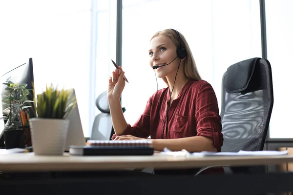 Belle travailleuse du centre d'appels dans les écouteurs travaille au bureau moderne — Photo