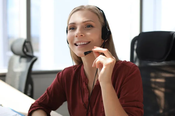 Belle travailleuse de centre d'appels souriante dans les écouteurs travaille au bureau moderne — Photo