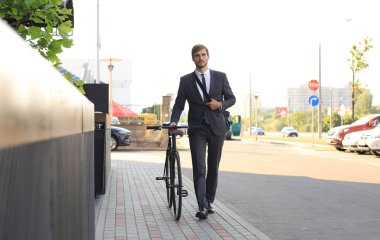 Şehirde sokakta bisikletle yürüyen pensive genç işadamı.