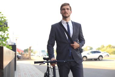 Şehirde sokakta bisikletle yürüyen pensive genç işadamı.