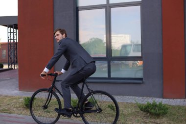 Şehirde bisiklete binen yakışıklı genç işadamı. Ekolojik ulaşım kavramı. 