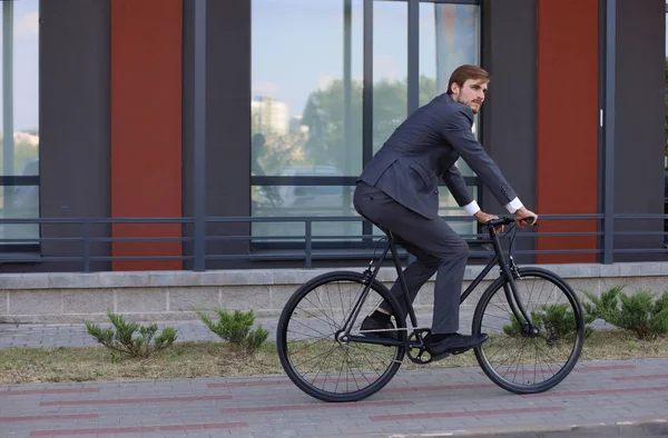 Schöner junger Geschäftsmann, der mit dem Fahrrad in der Stadt unterwegs ist. Ökologisches Verkehrskonzept. — Stockfoto