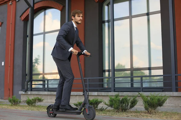 Pria bisnis muda menggunakan skuter listrik di jalan kota. Konsep transportasi ekologi dan modern . — Stok Foto