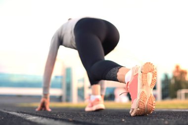 Stadyumdaki başlangıç çizgisinde başlama çizgisini bekleyen bayan koşucu