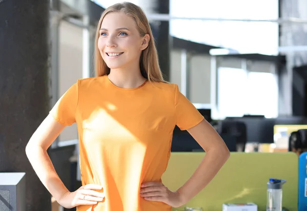 Femme d'affaires attrayante en tenue décontractée intelligente regardant la caméra et souriant tout en se tenant dans le bureau — Photo