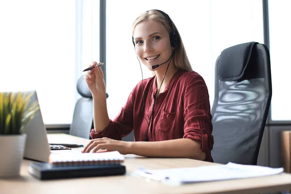 Krásná usmívající se call centrum pracovník ve sluchátkách pracuje v moderní kanceláři — Stock fotografie