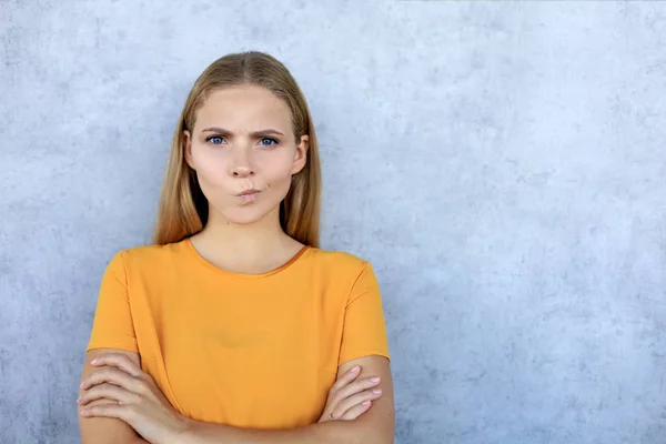 Portrait of a beautiful confused young blonde woman standing isolated over grey background — Stock Photo, Image