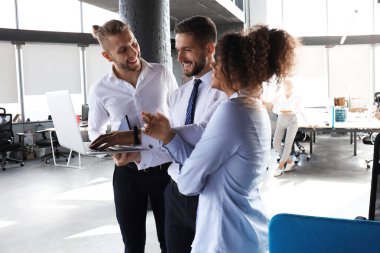 Modern iş adamları grubu ofis koridorunda dururken dizüstü bilgisayar ve gülümseyerek çalışıyoruz