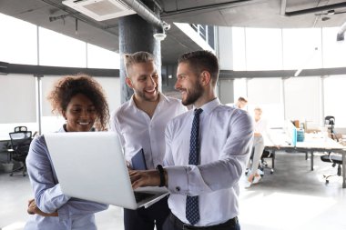 Modern iş adamları grubu ofis koridorunda dururken dizüstü bilgisayar ve gülümseyerek çalışıyoruz