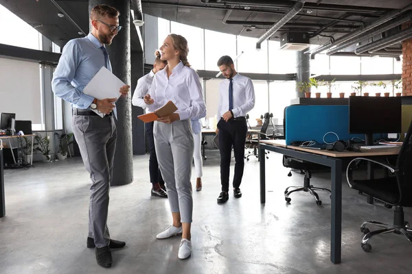Група сучасних бізнесменів розмовляє і посміхається, стоячи в офісному коридорі — стокове фото