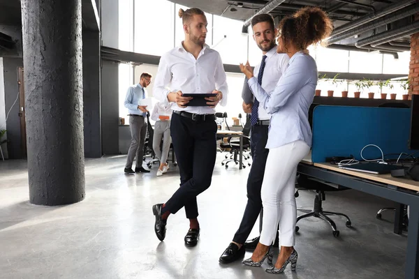 Gruppe moderner Geschäftsleute spricht und lächelt, während sie im Büroflur steht — Stockfoto