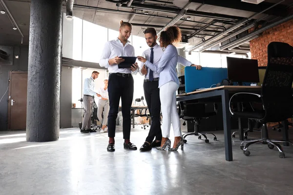 Gruppe moderner Geschäftsleute spricht und lächelt, während sie im Büroflur steht — Stockfoto