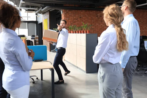Коллеги по бизнесу выводят уволенного сотрудника из офиса, показывая дерьмо — стоковое фото