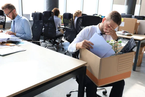 Triste trabalhador demitido está levando seus suprimentos de escritório com ele do escritório — Fotografia de Stock