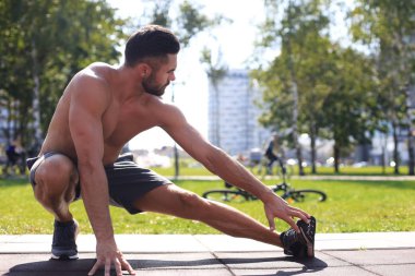 Sportif adam dışarıda bacaklara egzersiz yaptırıyor.