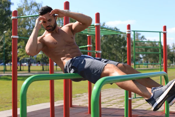 Atleta muscular activo haciendo ejercicios abdominales y crujidos al aire libre, entrenando —  Fotos de Stock