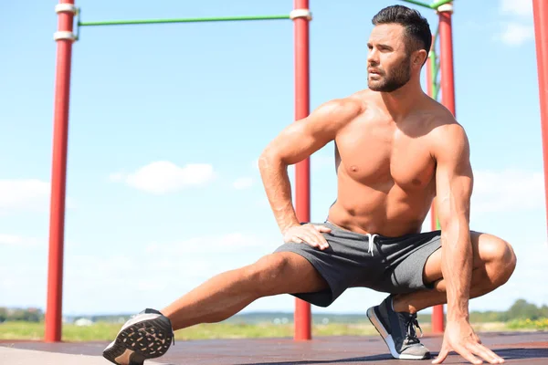 Hombre deportivo haciendo ejercicios de estiramiento para piernas al aire libre — Foto de Stock