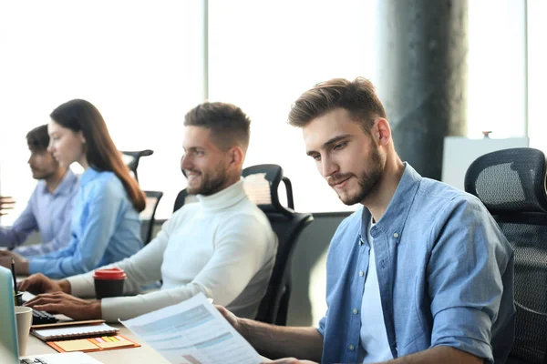 Giovani colleghi moderni in abbigliamento casual intelligente che lavorano insieme mentre trascorrono del tempo nell'ufficio creativo . — Foto Stock