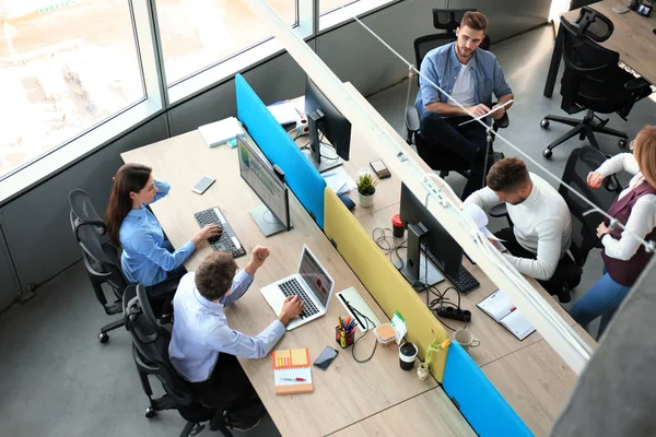 Bovenaanzicht van jonge moderne collega's in slimme vrijetijdskleding, samen te werken terwijl de tijd doorbrengen in het kantoor. — Stockfoto