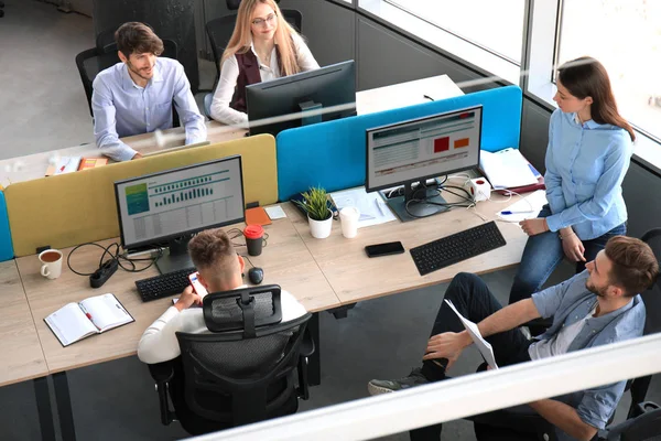 Vista superior de los jóvenes colegas modernos en ropa casual inteligente trabajando juntos mientras pasan tiempo en la oficina . —  Fotos de Stock