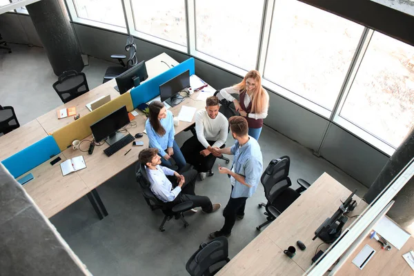 Vista superior de los jóvenes colegas modernos en ropa casual inteligente trabajando juntos mientras pasan tiempo en la oficina . —  Fotos de Stock