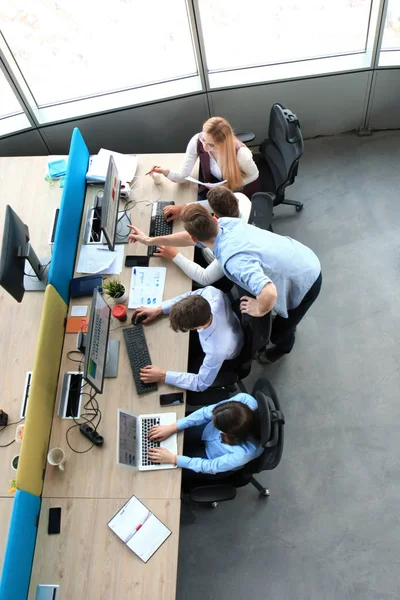 Vista superior de los jóvenes colegas modernos en ropa casual inteligente trabajando juntos mientras pasan tiempo en la oficina . —  Fotos de Stock