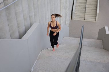Merdivenlerde koşan bir atlet. Kadın sporu dışarıda koşuyor.