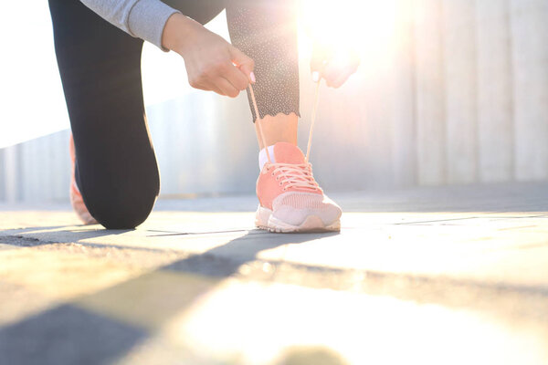 Крупный план неузнаваемой спортивной женщины, завязывающей спортивную обувь во время вечерней пробежки на открытом воздухе
