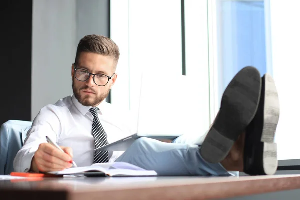 Knappe zakenman zittend met benen op tafel en het gebruik van laptop in Office — Stockfoto