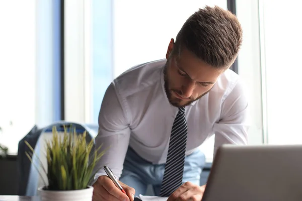 Empresario moderno enfocado que trabaja y toma notas en su oficina moderna — Foto de Stock