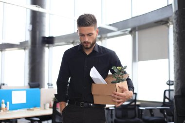 Üzgün işçi ofis malzemelerini yanında götürüyor.