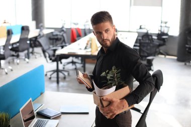 Üzgün işçi ofis malzemelerini yanında götürüyor.