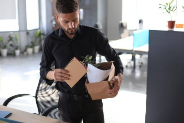 Üzgün işçi ofis malzemelerini yanında götürüyor.