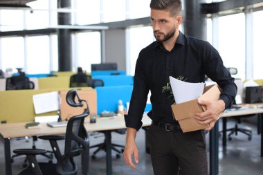 Üzgün işçi ofis malzemelerini yanında götürüyor.