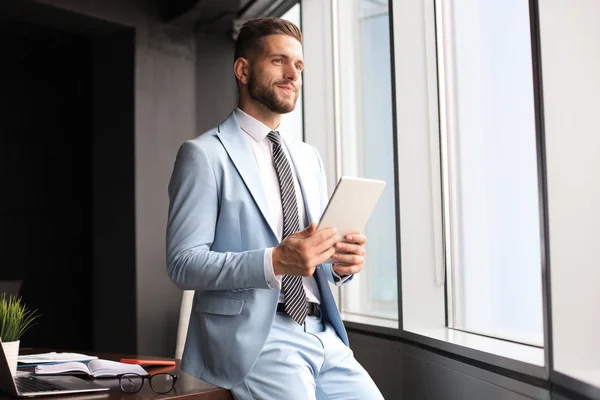 Jonge moderne zakenman die werkt met behulp van digitale tablet terwijl hij op kantoor zit — Stockfoto