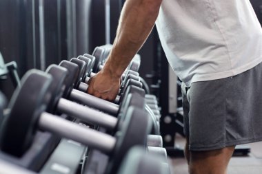 Spor salonunda dumbbells ile egzersizleri gösteren eğitim fitness adam.
