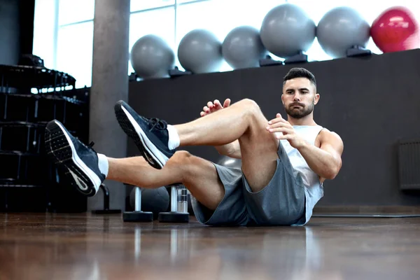 Homem desportivo alongamento e aquecimento fazendo exercícios especiais para os músculos antes de trabalhar seu corpo para fora . — Fotografia de Stock