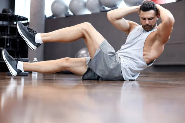 Спортивний чоловік розтягується і робить спеціальні вправи для м'язів, перш ніж відпрацювати своє тіло . — стокове фото