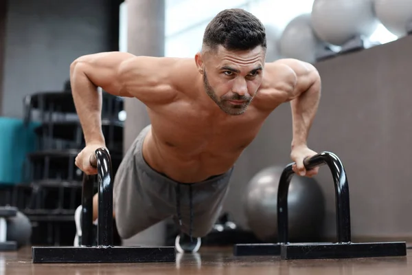 Dopasowanie i muskularny Człowiek robi poziome push-upy z barów w siłowni. — Zdjęcie stockowe