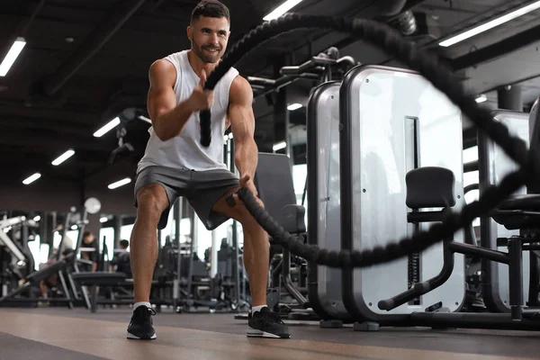 Atlético jovem com corda de batalha fazendo exercício no ginásio de fitness de treinamento funcional. — Fotografia de Stock