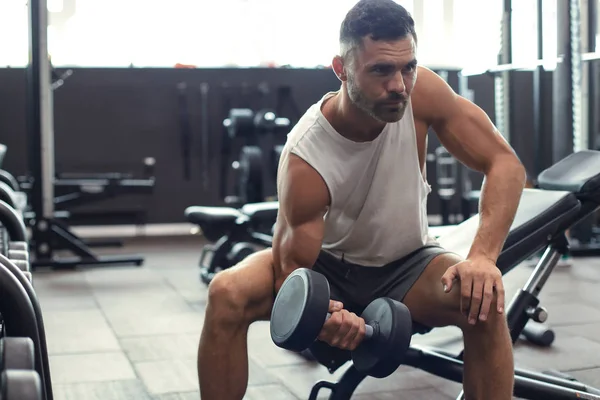 Вмістити і м'язистий чоловік робить біцепси тренувань з гантелями в спортзалі, копіювати простір . — стокове фото