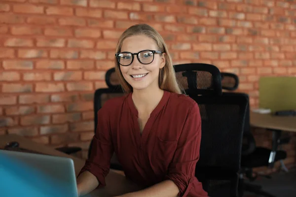 Hermosa mujer de negocios sonriente está sentada en la oficina y mirando a la cámara — Foto de Stock