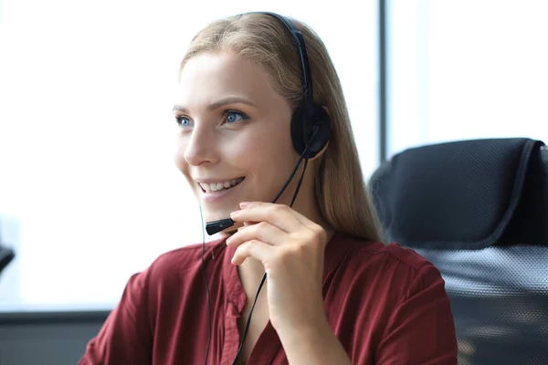 Prachtige glimlachende call center werknemer in hoofdtelefoon werkt op modern kantoor — Stockfoto