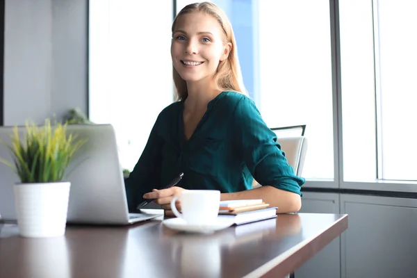 Belle femme d'affaires souriante est assise dans le bureau et regardant la caméra — Photo