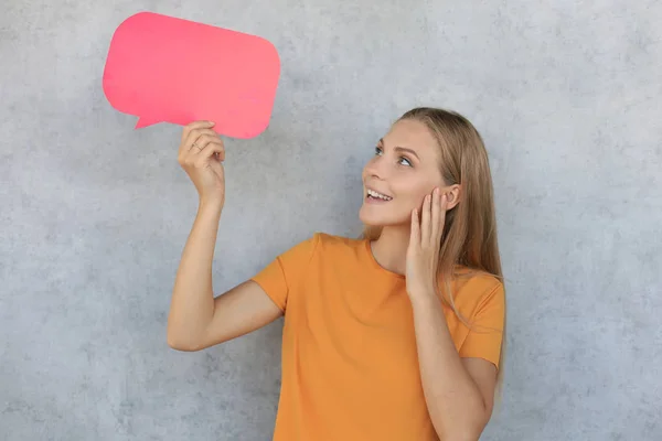 Gelukkig mooie jonge blonde vrouw staande geïsoleerd over grijze achtergrond, het houden van lege toespraak bubble — Stockfoto