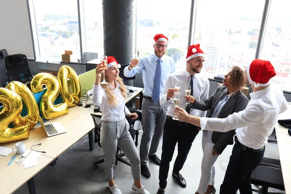 Деловые люди празднуют праздник в современном офисе, пьют шампанское и веселятся в коворкинге. С Новым 2020 годом и Рождеством! . — стоковое фото