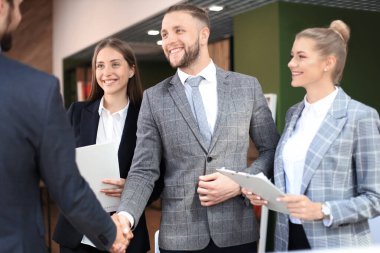 İş ortakları iş yerlerindeki iş eşyalarının üzerinden el sıkışıyor.