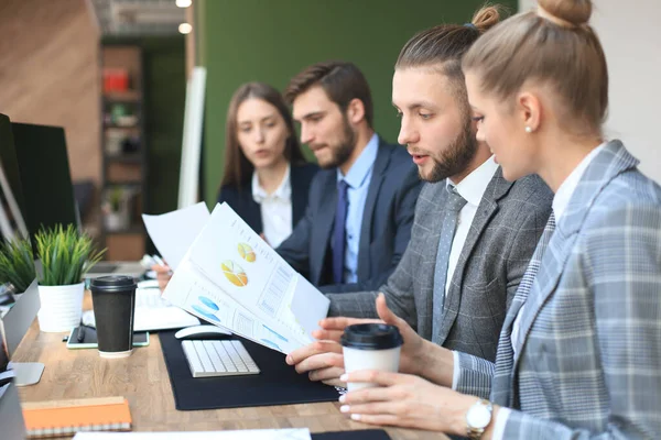 Gruppo di giovani imprenditori che lavorano, comunicano mentre sono seduti alla scrivania dell'ufficio insieme ai colleghi . — Foto Stock